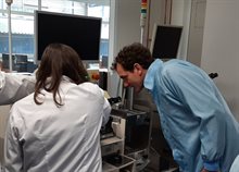 Two people in lab coats looking at a machine for chip packaging