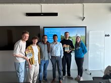 Lecturer surrounded by five students holding his thesis Pd