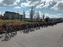 Long row of parked bikes from students visiting a campus under a clouded sky