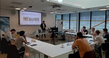 Young lecturer on semiconductor packaging standing in front of students sitting in a u-form set-up