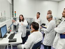 Five scientists listening to a female lecturer explaining the use of a confocal scanning microscope