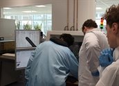 Young student trying to work with a die placer while supervised by a technician and a fellow student