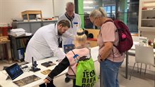 Two researchers showing a child and parent the latest chip packages
